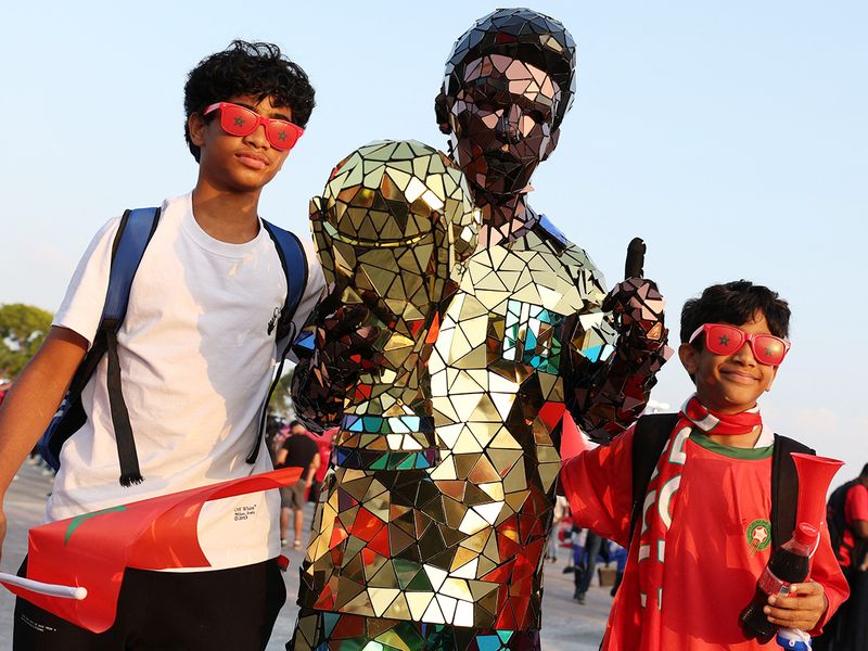 A performer poses with Morocco fans outside the Khalifa International Stadium in Doha before the match. 
