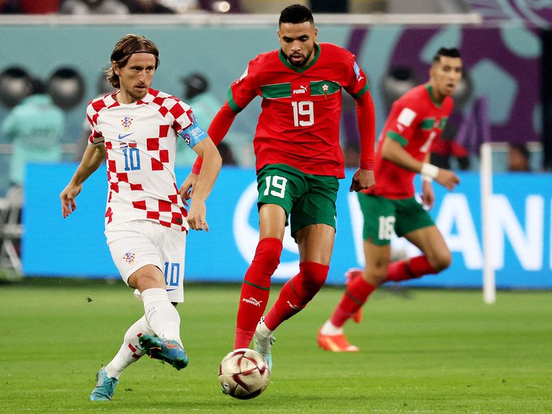 Croatia's midfielder Luka Modric (L) plays the ball next to Morocco's forward Youssef En-Nesyri. 