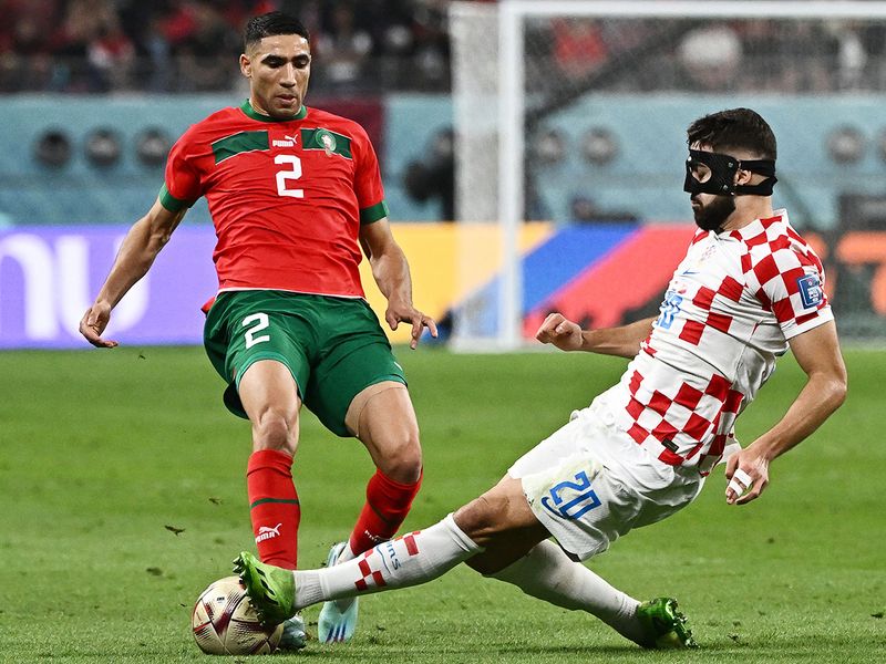 Morocco's defender Achraf Hakimi (L) fights for the ball with Croatia's defender Josko Gvardiol. 