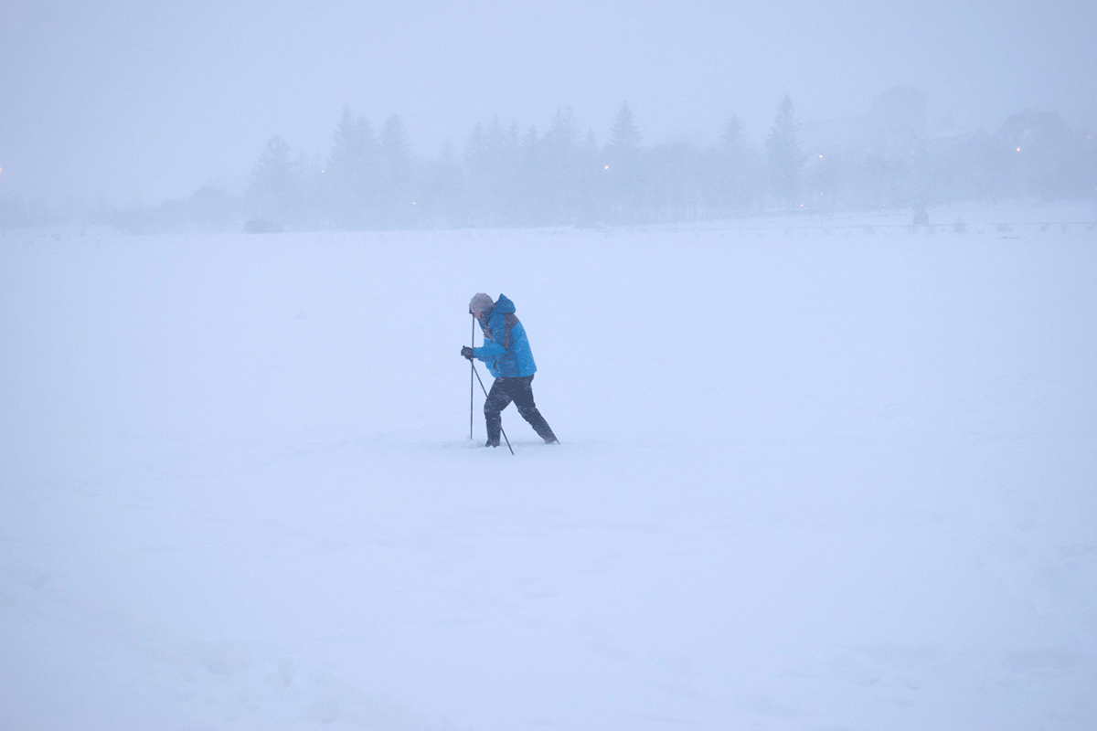  A man skiis on the frozen and snow-covered Tjörnin lake during snowfall in downtown Reykjavik, Iceland on December 17, 2022. - The first snow started falling and intensified on December 17, covering the Icelandic capital in white. 