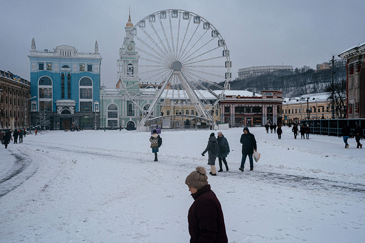 Pedestrians walk in the snow after a fresh snowfall in the center of the Ukrainian capital Kyiv on December 15, 2022, amid the Russian invasion of Ukraine. 