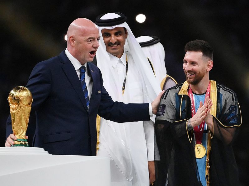 Argentina's Lionel Messi receives the World Cup trophy from FIFA President Gianni Infantino 