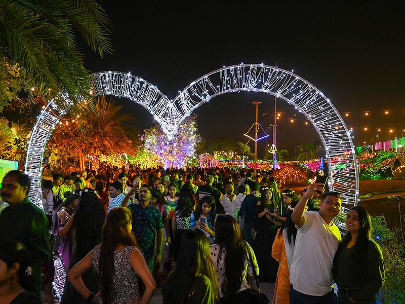 People gather at the sea promenade, lit up during sunset on New Year’s Eve in Mumbai 