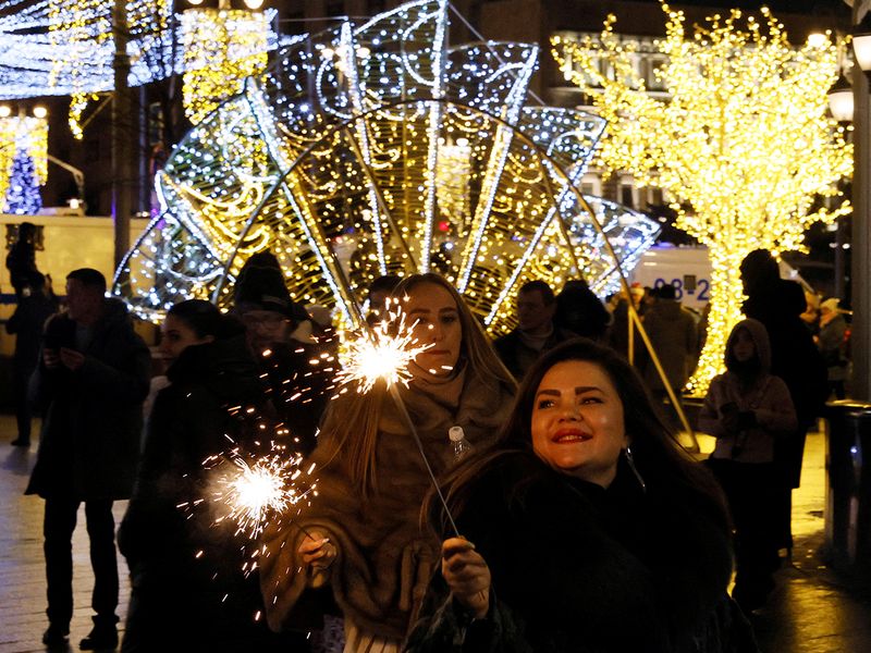 Women carry burning sparklers during the New Year's Eve celebrations in central Moscow, Russia