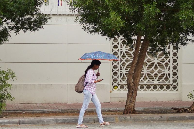 A pedestrian uses her umbrella to keep from getting wet. 