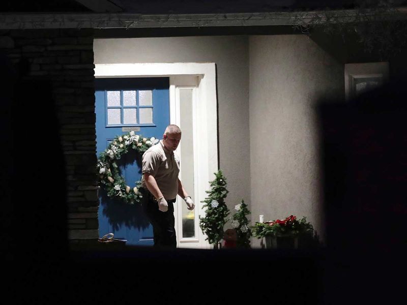 A law enforcement official stands near the front door of the Enoch, Utah,