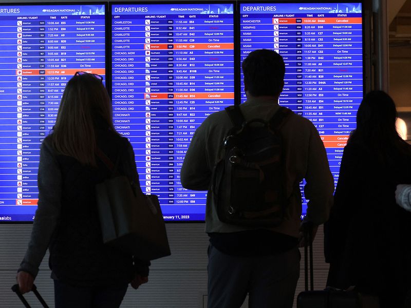 Travellers look at a flight information board at Ronald Reagan Washington National Airport in Arlington, Virginia. 