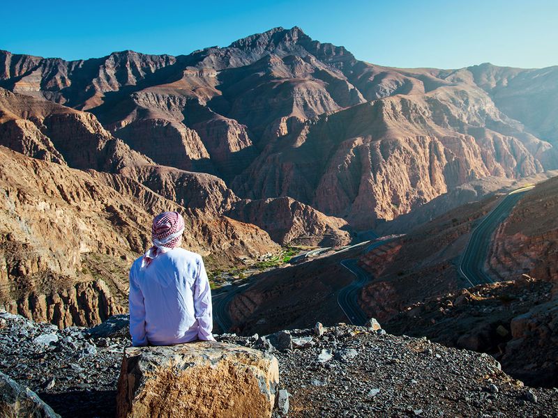 Arab man enjoying the view at the Jebel Jais desert sandstone mountain in Ras al Khaimah UAE