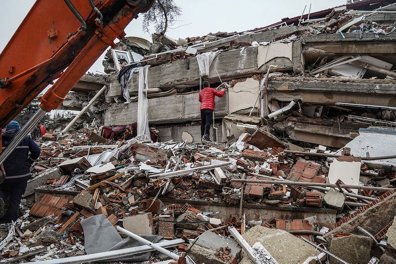 A man searches for people  in the rubble of a destroyed building in Gaziantep, Turkey, Monday, Feb. 6, 2023. A powerful quake has knocked down multiple buildings in southeast Turkey and Syria and many casualties are feared.
