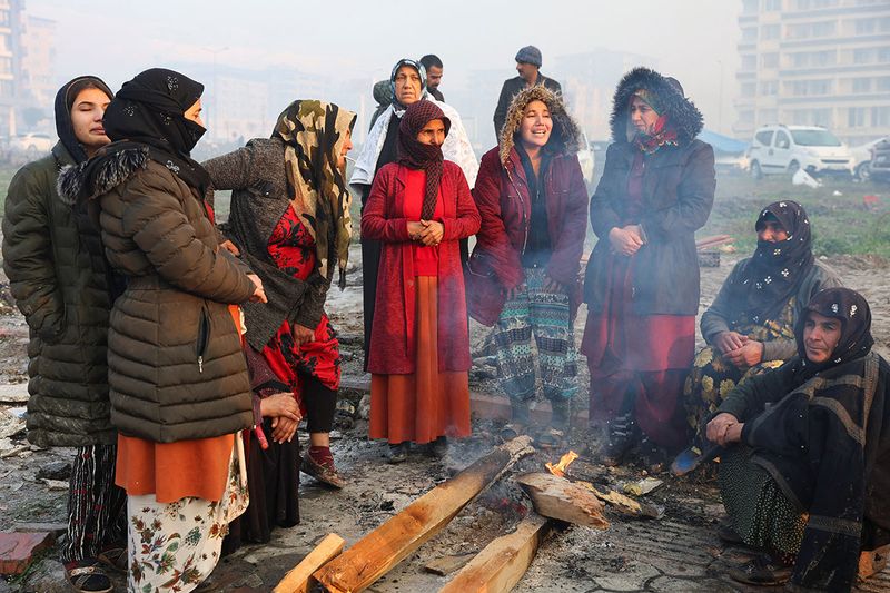 People gather around a fire following an earthquake in Hatay, Turkey, February 7, 2023. 