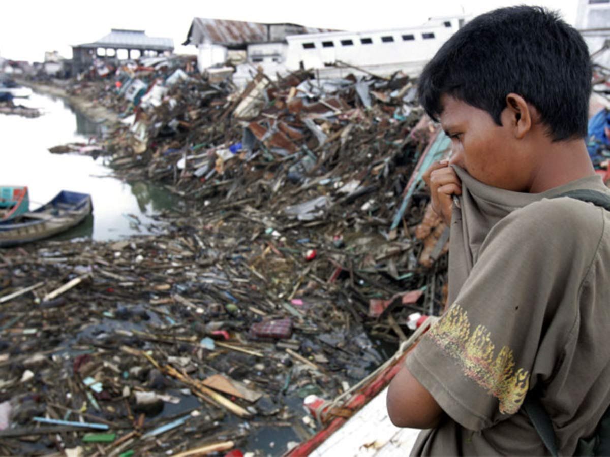 In this Saturday Jan. 1, 2005 file photo, a man looks at a floating debris and dead bodies on Aceh River in Banda Aceh, Indonesia. The tsunami that struck on Dec. 26, 2004, was one of the world’s worst natural disasters in modern times.