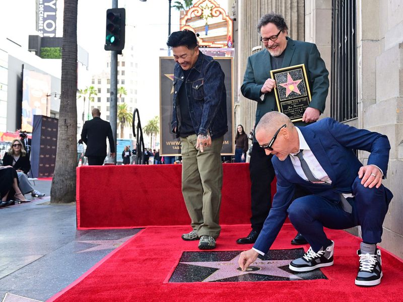Hollywood actor Robert Downey Jr. places the first piece of gum on Jon Favreau's unveiled Hollywood Walk of Fame star at Los Angeles, February 13.