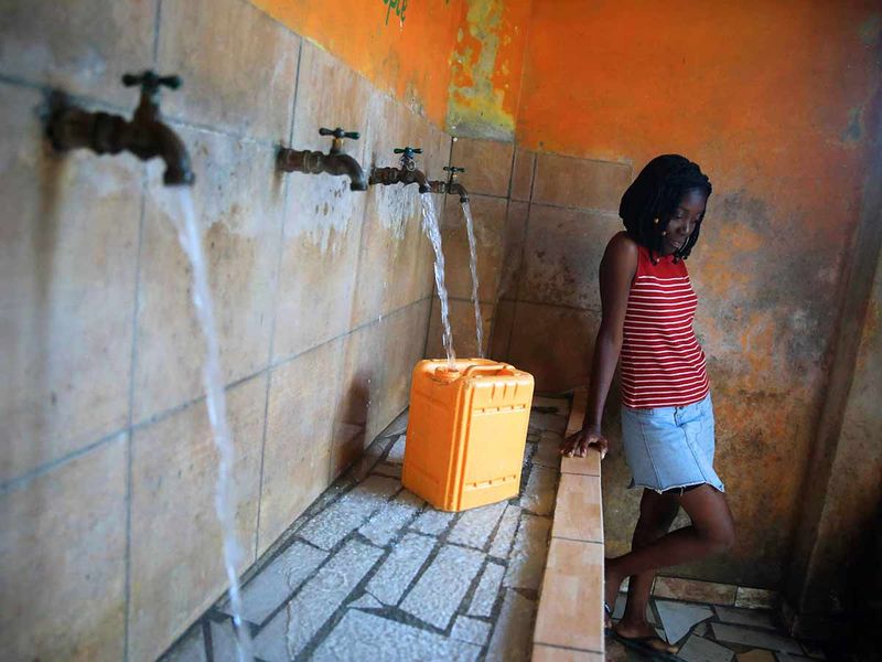 A resident without running water at home fills a container at a water fill station, a day ahead of World Water Day, in Port-au-Prince, Haiti, Tuesday, March 21, 2023.