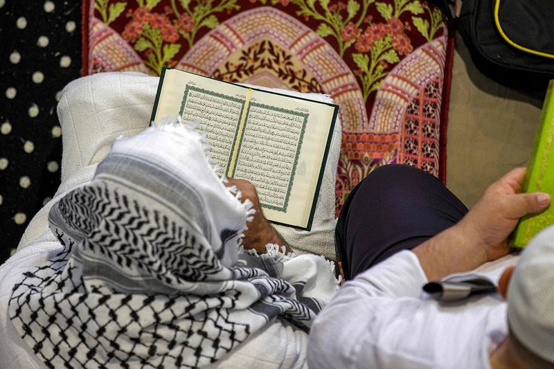 A Muslim worshipper reads from the Koran, Islam's holy book, at the Grand Mosque in the holy city of Mecca during the second Friday prayers in the holy month of Ramadan on March 31, 2023.