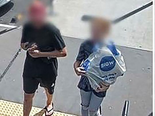 An undated handout framegrab received on April 6, 2023 from the Queensland Police Service shows a man (L) carrying a rare, wild platypus at a train station near Brisbane. -