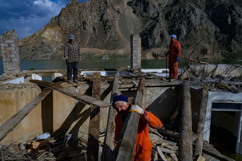 Local residents attempt to retrieve items from a home in the flooded town of Yusufeli, submerged by an artificial lake caused by a dam retaining the flow of the Coruh river (also referred to as Chorokhi), Artvin province, in northeastern Turkey, on April 5, 2022. - The Yusufeli Dam and its Hydroelectric Power Plant Project in the Eastern Black Sea Region has started to hold water, with the electricity production expected to start in May 2023. With a total water storage volume of approximately 2.2 billion cubic meters, the double curvature concrete arch dam is Turkey’s highest with a height of 275 meters. 
