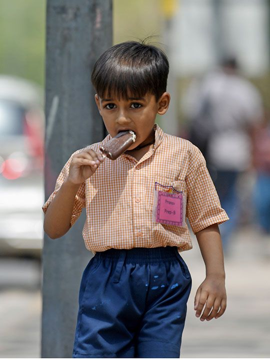  A student eats ice cream to beat the heat on a hot summer day, in New Delhi.