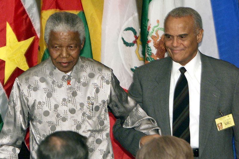 Former South African President Nelson Mandela (L) is escorted back to his seat by Harry Belafonte  the U.N. General Assembly Special Session on Children in New York, May 9, 2002. 