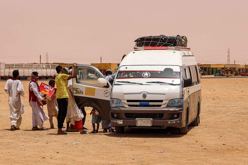 Pedlars offer snacks for sale to people aboard a passenger bus at the Multaga rest-stop near Ganetti in Sudan's Northern State on April 25, 2023.