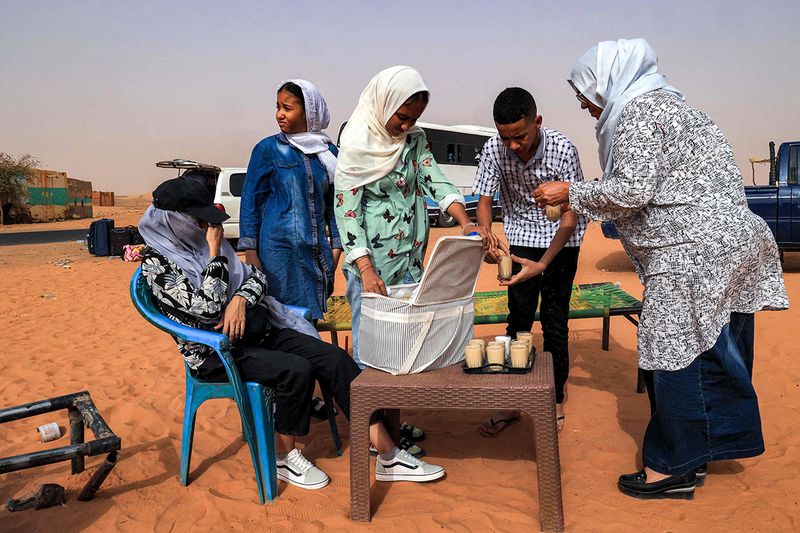People stop for refreshments at a rest-point by a desert road at al-Gabolab in Sudan's Northern State, about 100 kilometres northwest of the capital, on April 25, 2023. 