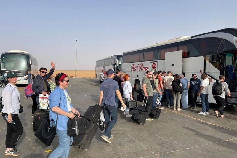 Ukrainian civilians wait to board a bus after getting evacuated, in Argeen, Sudan April 2023, in this handout image