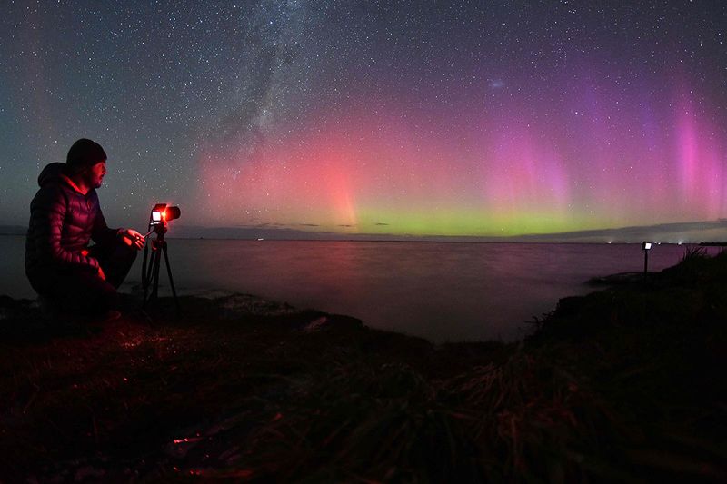  A photographer takes pictures of the Aurora Australis, also known as the Southern Lights, as it glows on the horizon over waters of Lake Ellesmere on the outskirts of Christchurch on April 24, 2023.