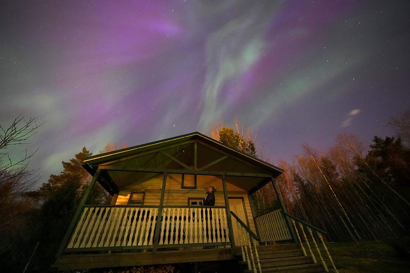 A woman watches northern lights (aurora borealis) over the village of Podolye, Russia, 70 kilometers (43 miles) east of St. Petersburg, on Sunday, April 23, 2023.