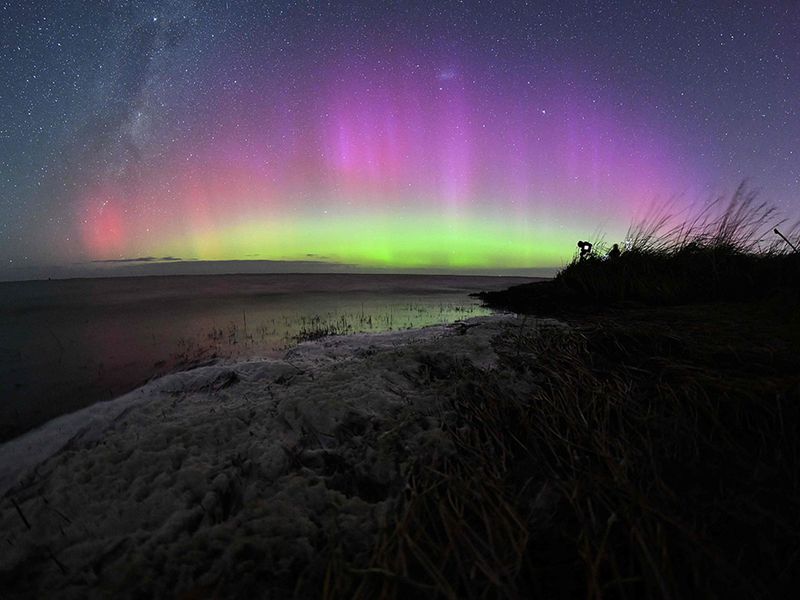 The Aurora Australis, also known as the Southern Lights, glow on the horizon over waters of Lake Ellesmere on the outskirts of Christchurch on April 24, 2023.