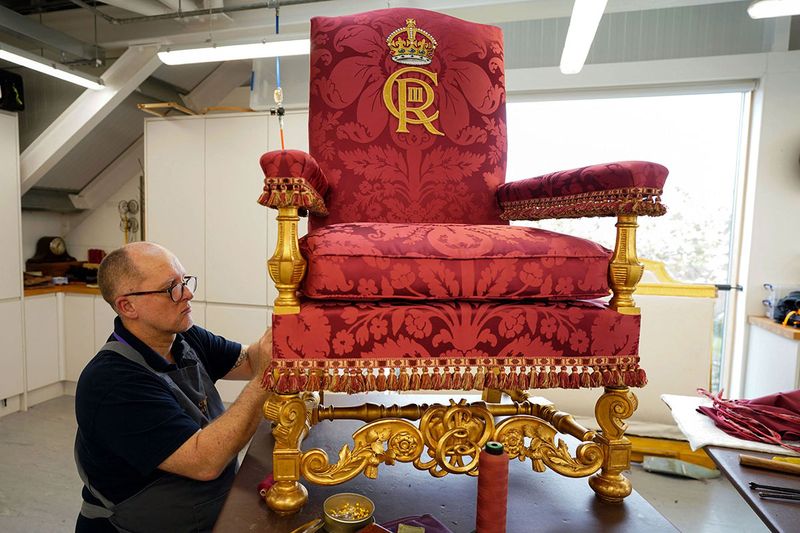 A member of the Royal Household works on the Chair of Estate for Britain's King Charles III at Frogmore Workshops in Windsor, west of London, on April 21, 2023, ahead of the coronation of Britain's King Charles III and the Britain's Camilla, Queen Consort on May 6.