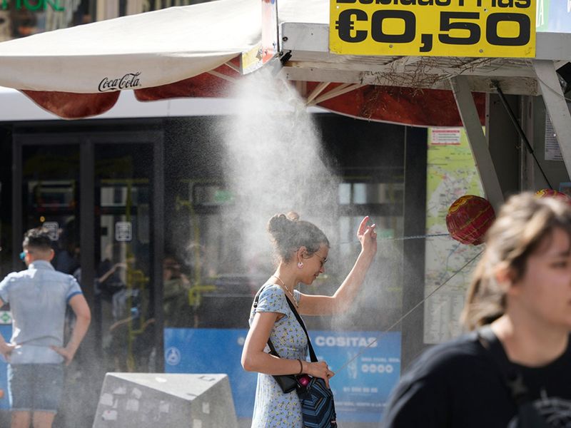 A customer stands under a cooling mist spray at a street kiosk during high temperatures in central Madrid, Spain, on Thursday, April 27, 2023. Spring in Spain will resemble the middle of the summer this week as thermometers rise above 30 degrees Celsius (86 Fahrenheit) and some regions are forecast to hit 40 Celsius (104 Fahrenheit). 