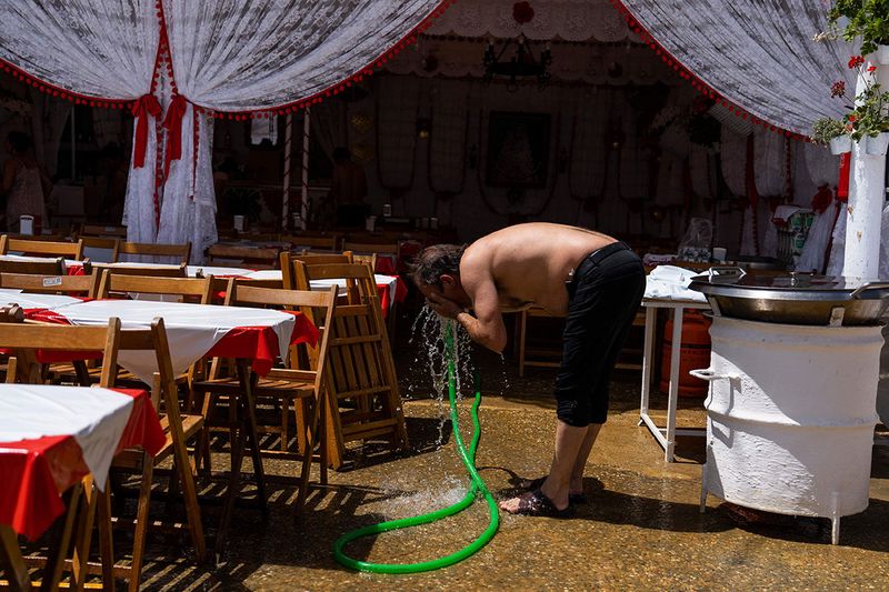 A man refreshes himself with a water hose outside a 'caseta' (tent where food and drinks are served) in the annual traditional April Fair in Seville, Spain.
