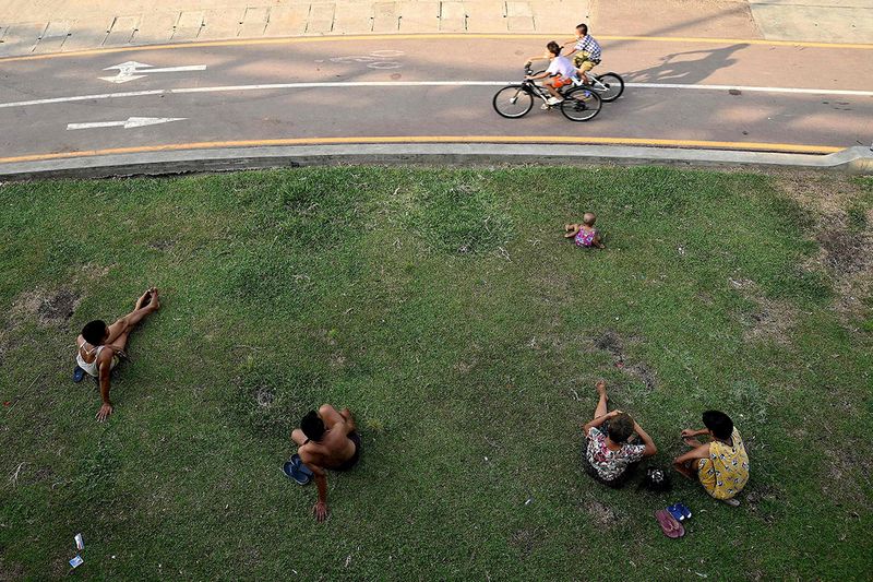 People sit in the shade to shelter from the sun during heatwave conditions in Yangon on May 8, 2023. 