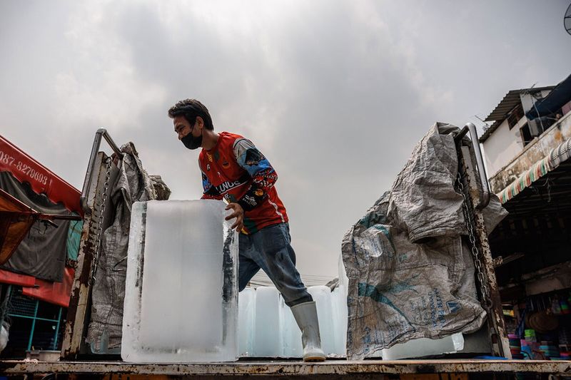 Workers unload blocks of ice at a wet market during a heatwave in Bangkok, Thailand.  