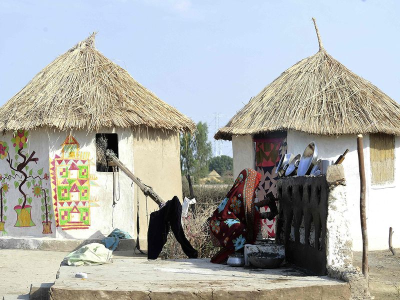 A woman applies mud to her flood-resistant open kitchen at Sanjar Chang village in Tando Allahyar district.  
