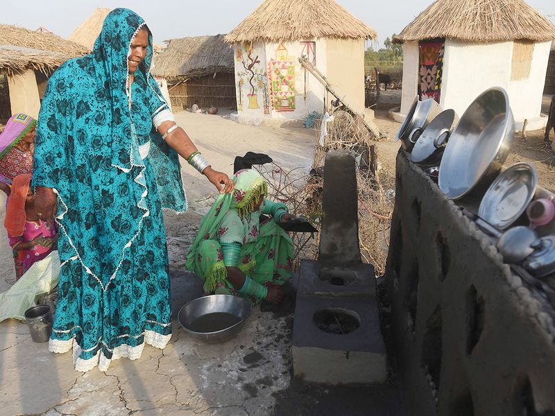 Champa (left), a master trainer in making earthen stoves lifted off the floor, trains a woman at Sanjar Chang village in Tando Allahyar district. 