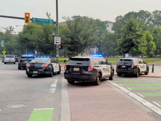Police vehicles are seen parked near a park where, according to the police, a gunman opened fire, in Richmond