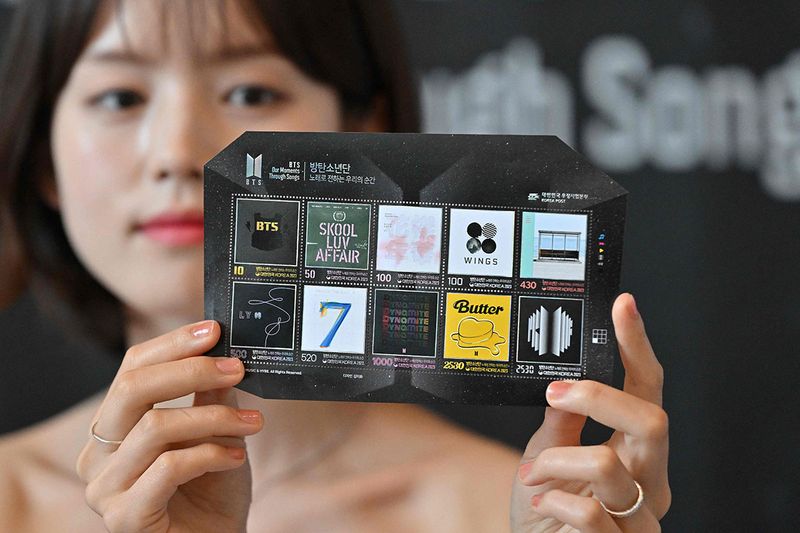 A model shows a BTS 10th anniversary postage stamp during its unveiling event at Seoul Central Post Office in Seoul on June 12, 2023. Seoul this week marks 10 years of megastars BTS, the supergroup credited with bringing K-pop into the global mainstream and generating billions of dollars for the South Korean economy.