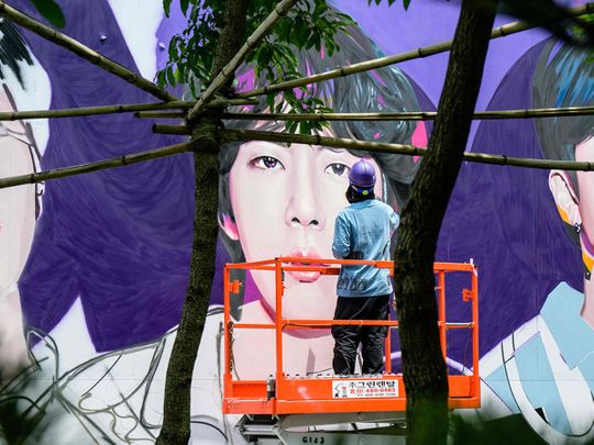 An artist spray paints a mural of K-pop megastars BTS in Seoul on June 12, 2023, on the occasion of the supergroup's 10-year anniversary. Fans of K-pop megastars BTS flocked to hotspots around Seoul on June 12 to mark the supergroup's 10-year anniversary, with South Korea unveiling a special commemorative stamp series to celebrate.