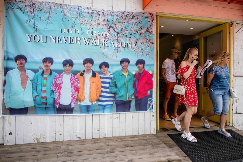 Customers leave a cafe with a poster of K-pop megastars BTS displayed outside the premises in Seoul.