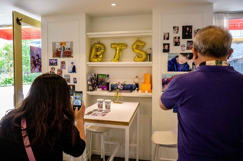 Customers take photos of balloons and pictures showing K-pop megastars BTS inside a cafe in Seoul on June 12, 2023, on the occasion of the supergroup's 10-year anniversary. Fans of K-pop megastars BTS flocked to hotspots around Seoul on June 12 to mark the supergroup's 10-year anniversary, with South Korea unveiling a special commemorative stamp series to celebrate)