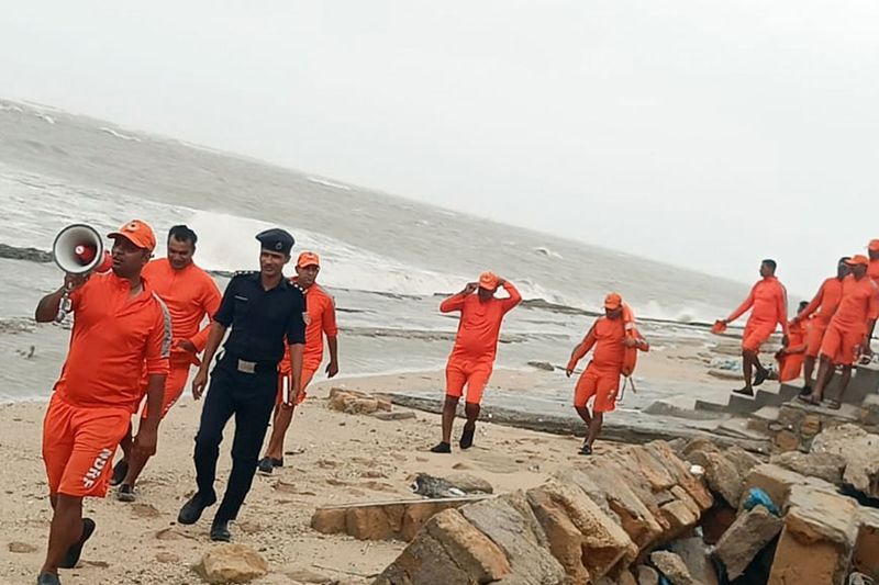 NDRF personnel alert and warn people near coastal and low-lying areas in view of the impending cyclone Biparjoy, in Kutch on Thursday.