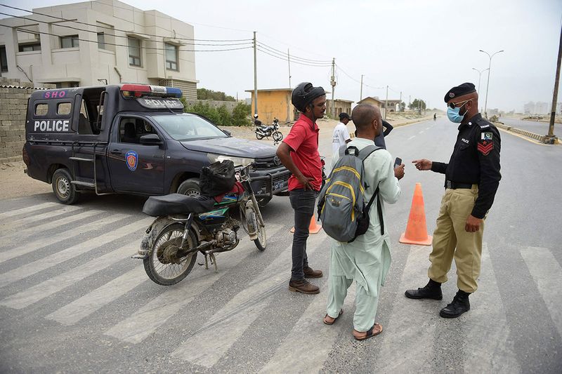 Policemen stop motorcyclists along a closed coastal road in Karachi on June 13, 2023, as cyclone Biparjoy makes its way across the Arabian Sea towards the coastlines of Pakistan.