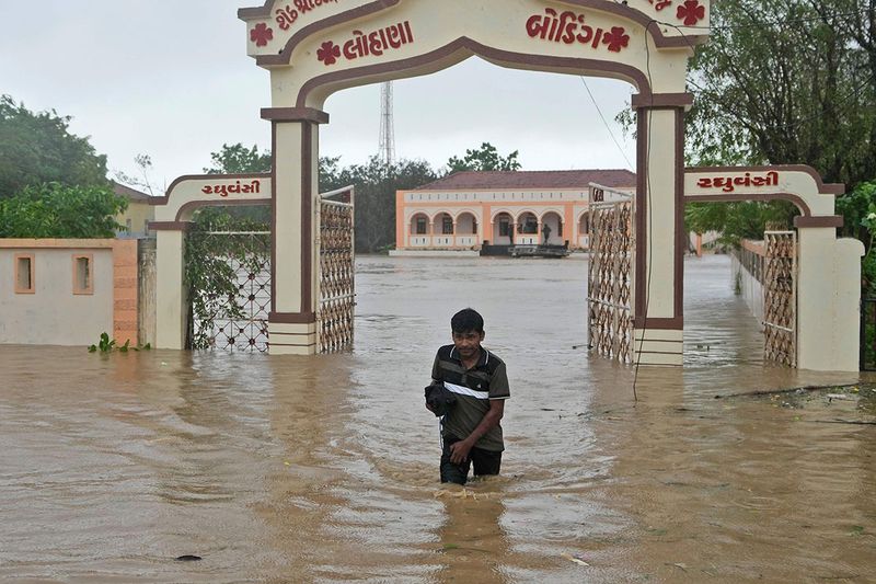 A man wades through flooded street following heavy winds and incessant rains after landfall of cyclone Biparjoy at Mandvi in Kutch district of Western Indian state of Gujarat.