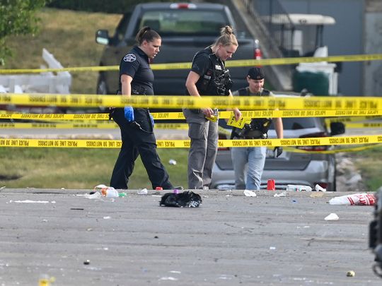 Investigators look over the scene of an overnight mass shooting at a strip mall in Willowbrook, Ill., Sunday, June 18, 2023.
