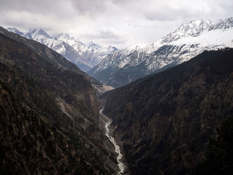 The Sutlej River flows in the valley below the tall snowy peaks in the Kinnaur district of the Himalayan state of Himachal Pradesh, India. 
