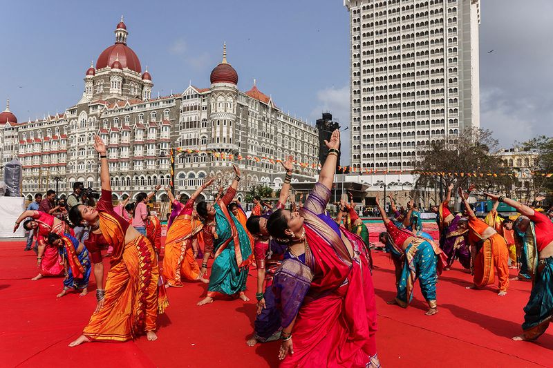 People perform yoga in front of Taj Hotel, in Mumbai.