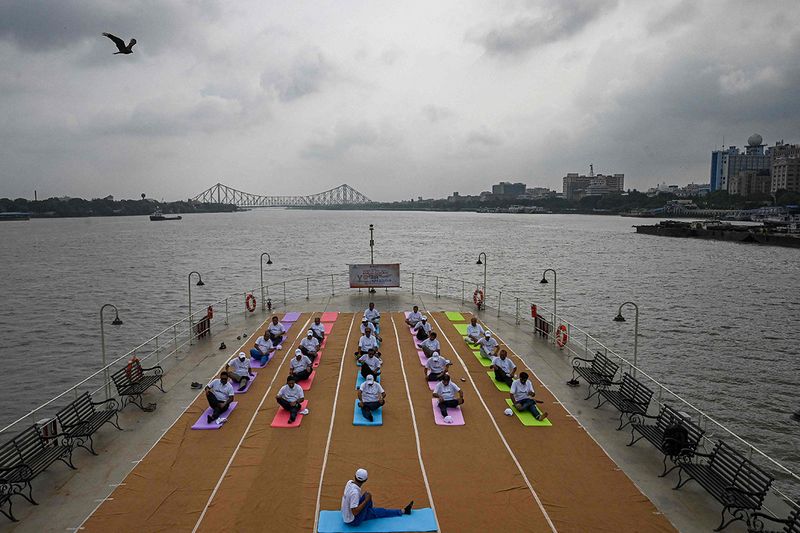 Port-Trust officials take part in a yoga session on the International Day of Yoga, on-board PS Bhopal sailing over river Hoogly in Kolkata on June 21, 2023. 