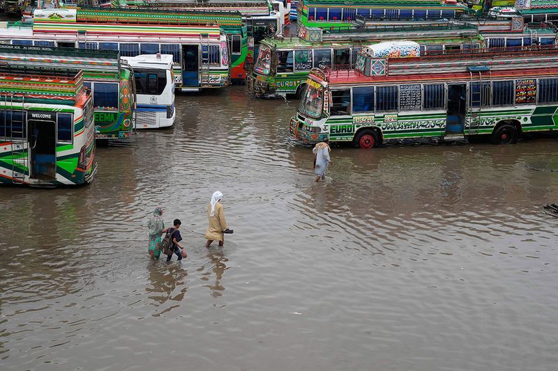 Passengers wade through a flooded bus terminal in Lahore.  The last time Lahore received such a deluge was 30 years ago, officials said.   