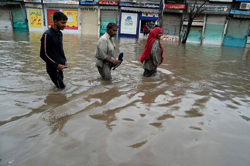 People wade through a flooded area caused by heavy monsoon rainfall in Lahore, Pakistan, Wednesday, July 5, 2023. Officials say heavy monsoon rains have lashed across Pakistan, killing a number of people.