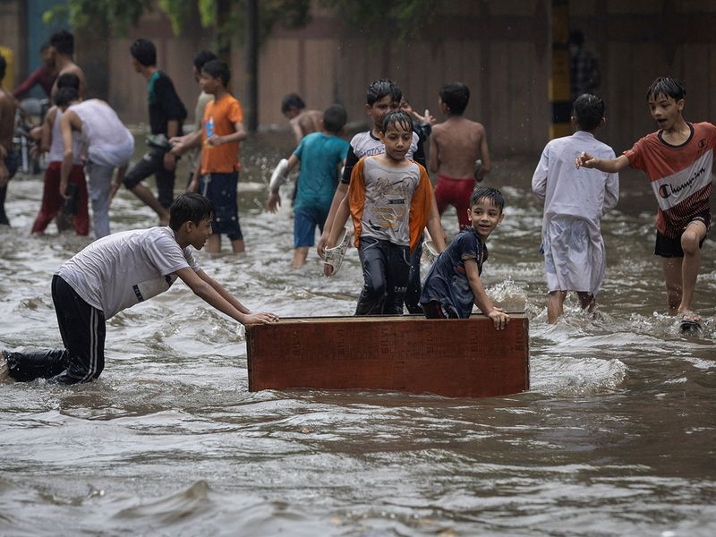 Children play on a flooded street after heavy rains in New Delhi, India, July 8, 2023. 